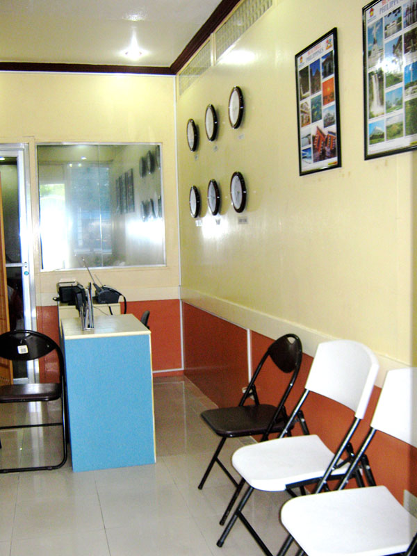 The same office from the counter: world clocks, waiting chairs and a service desk