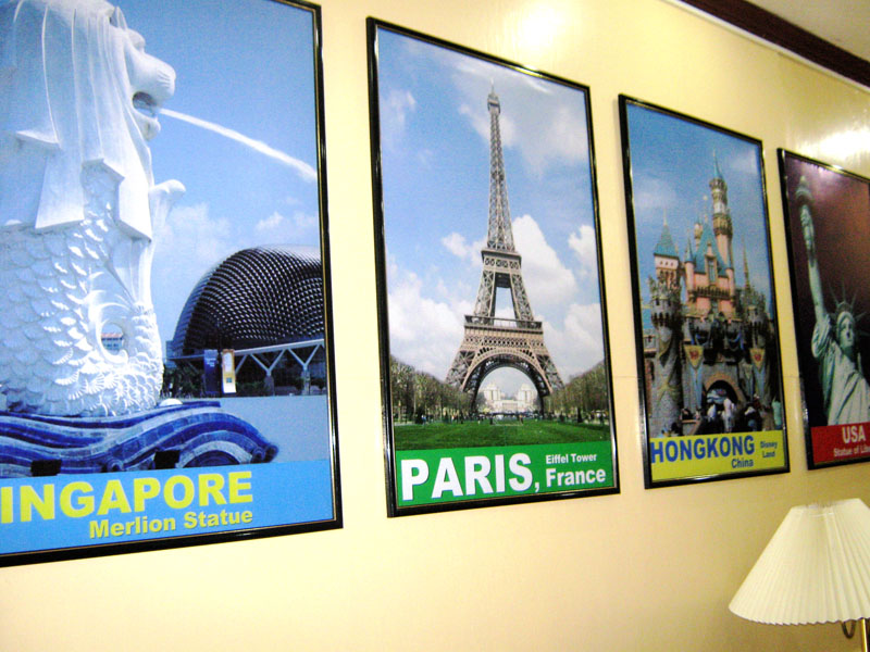 Travel posters of Singapore, Paris and Hong Kong on a yellow wall