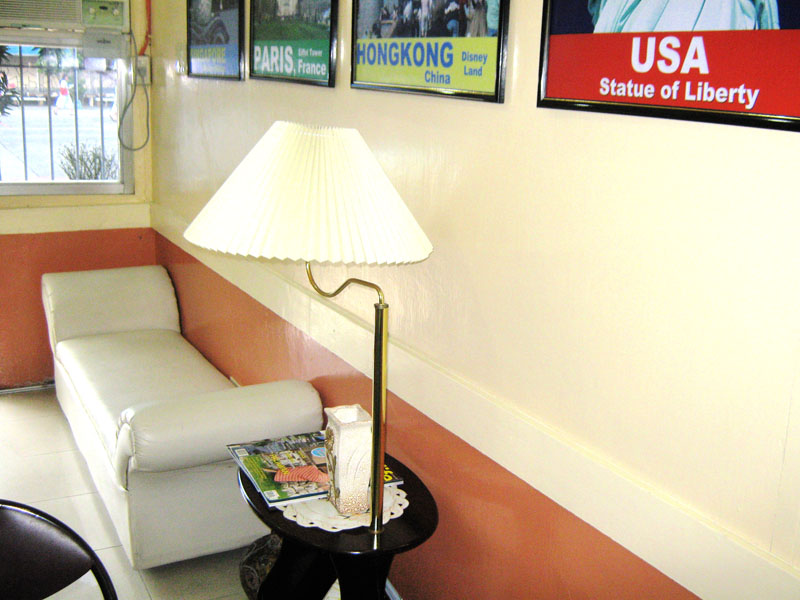 A lounge chair and floor lamp beneath posters of the United States and Hong Kong
