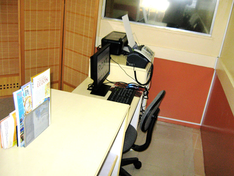 A desk with a computer, printer and travel brochures