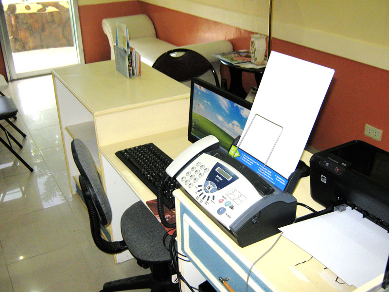 A front desk with a computer, fax machine and printer