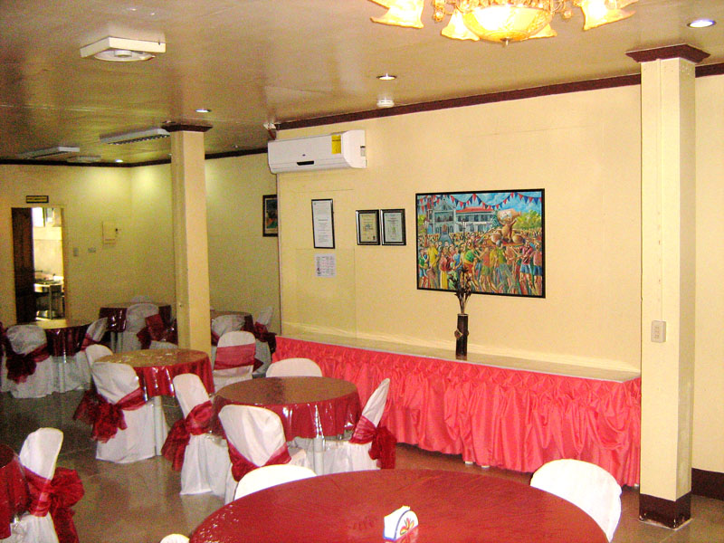 A dining room with round tables dressed in red and white linen