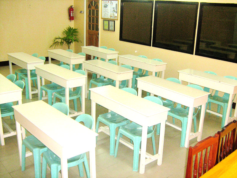 A classroom with white desks and aqua chairs