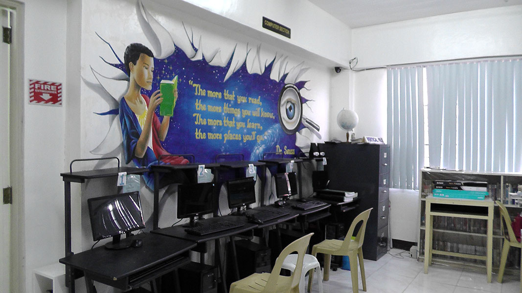 A row of computers beneath a painted reading mural