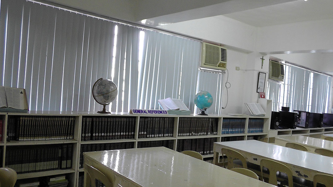 A library reading room with long tables, bookshelves and a globe