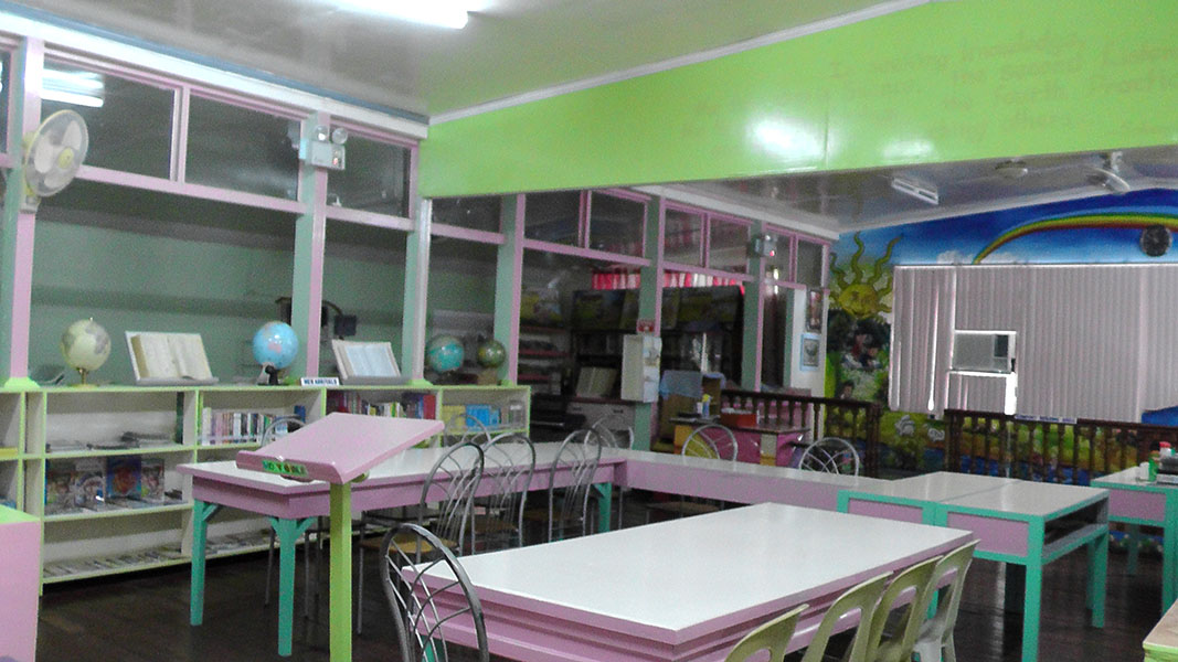 A reading room with pink tables and green walls
